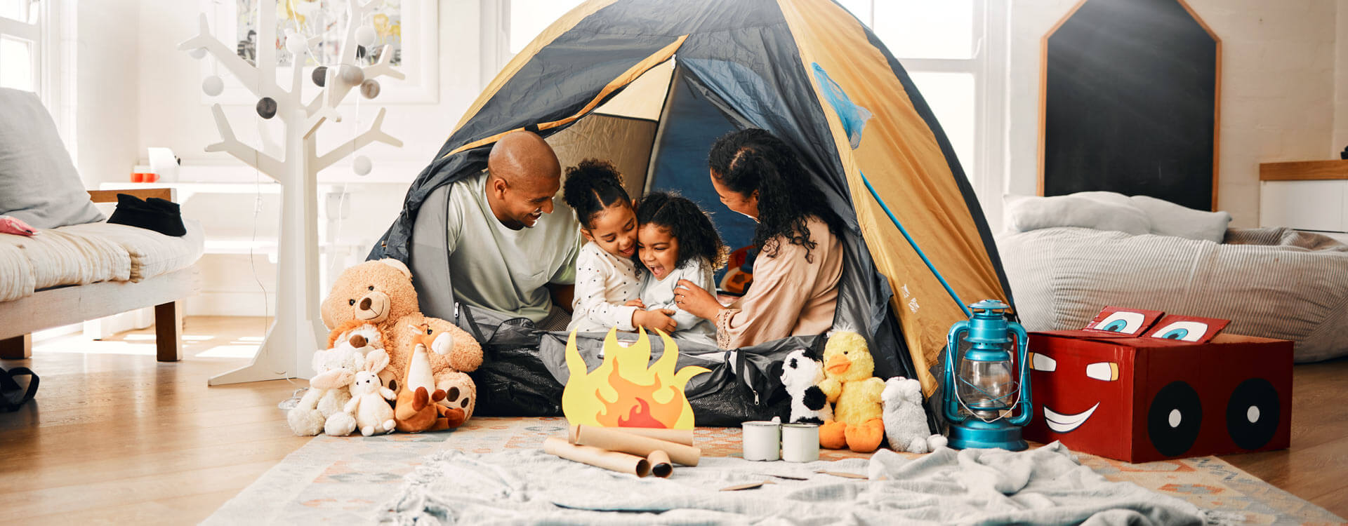 Family camping in a tent in their living room with toys around the tent